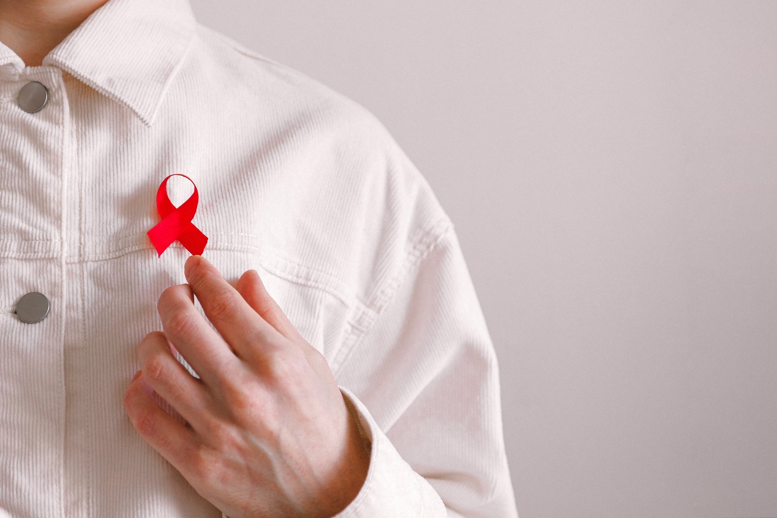 Man met een rood lint op zijn shirt op Wereld AIDS Dag